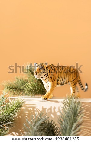 Tiger symbol of the Chinese new year 2022. Figurine of tiger with branches spruce tree on wooden stand on bright background. Copy space.