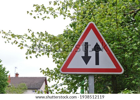 Triangular Road Sign with Direction Arrows on Metal Pole in Close Up