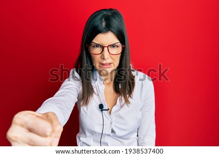 Young hispanic woman using lavalier microphone annoyed and frustrated shouting with anger, yelling crazy with anger and hand raised 