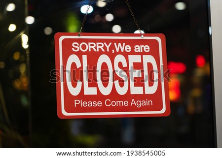 A Sign board of sorry we are closed hang on a door shop with reflections blurred bokeh background.                          