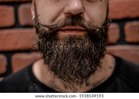 Close-up of handsome old-fashioned hipster tattooed and pierced on a brick background.