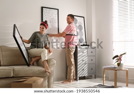 Couple decorating room with pictures together. Interior design Royalty-Free Stock Photo #1938550546