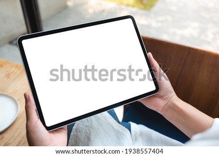 Mockup image of a woman holding digital tablet with blank white desktop screen in cafe Royalty-Free Stock Photo #1938557404