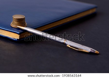 blue diary and pen on a black background. Planning and business concept