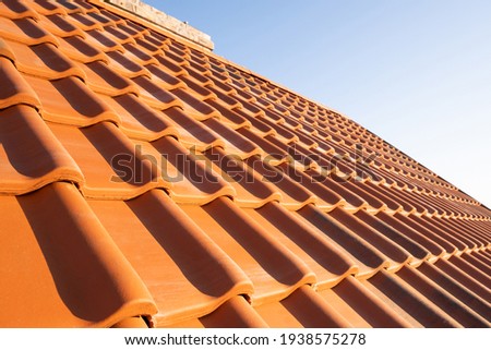 Overlapping rows of yellow ceramic roofing tiles covering residential building roof. Royalty-Free Stock Photo #1938575278
