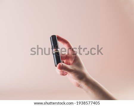 Close-up. Lipstick in the girl's hand. Powdery background