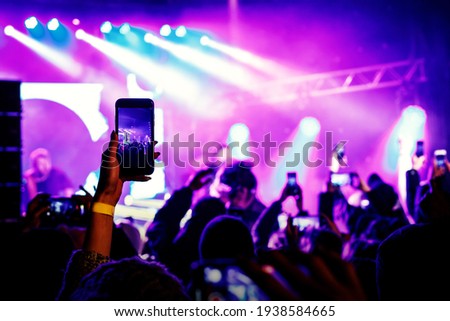 Using a smartphone in a public event. Holding a mobile phone in hands and shooting photo or video content