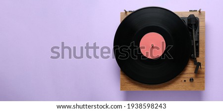 Modern turntable with vinyl record on light background, top view