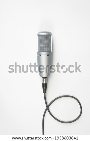 Professional studio microphone on a light background, top view. Broadcasting, sound recording, podcast concept. Vertical photo