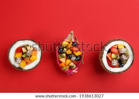 Delicious exotic fruit salad on red background, flat lay