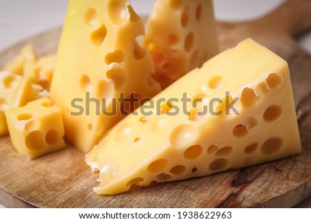 Pieces of delicious cheese on wooden board, closeup Royalty-Free Stock Photo #1938622963