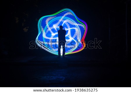 one person standing against beautiful blue and white circle light painting as the backdrop