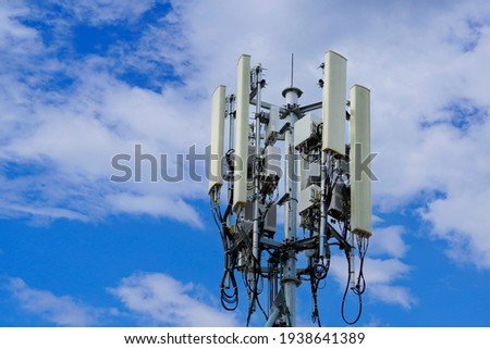 Telecommunication tower of 4G and 5G cellular. Macro Base Station. 5G radio network telecommunication equipment with radio modules and smart antennas mounted on a metal on cloulds sky background. Royalty-Free Stock Photo #1938641389
