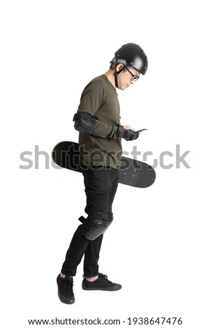 The Asian man with protective gear and skateboard standing on the white background.