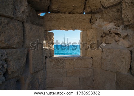 Beautiful view of mediterranean sea with a ship, framed by a window on Rhodes city walls. Dodecanese, Greece.