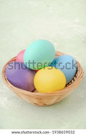 colorful easter eggs in a basket on green background with copy space