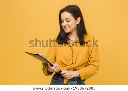 Concept photo of business lady holds papers. Wears yellow shirt, isolated yellow color background