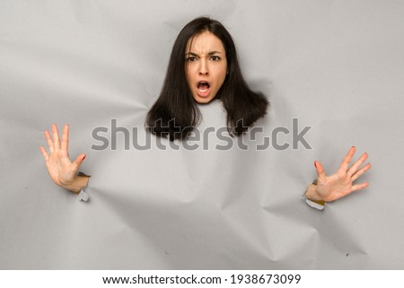 Concept photo of young female tearing paper and peeking out hole, shocked about commercial offer on copy space, isolated grey color background