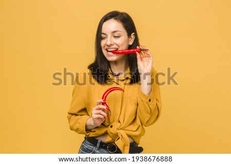 Concept photo of young female holds red paper, looks like she love spicy food. Wears yellow shirt, isolated yellow color background