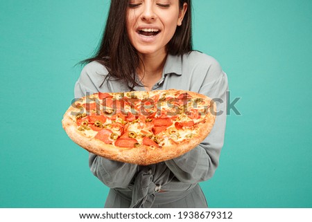 Photo of cute lady holds pizza, enjoy junk food. Wears grey shirt, isolated turquoise color background