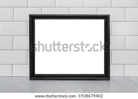 Black empty black picture frame on white subway tile wall aa