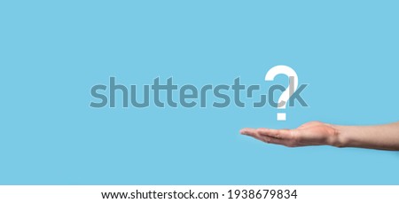 Male hand holding question mark icon on blue background.Banner with copy space. Place for text Royalty-Free Stock Photo #1938679834