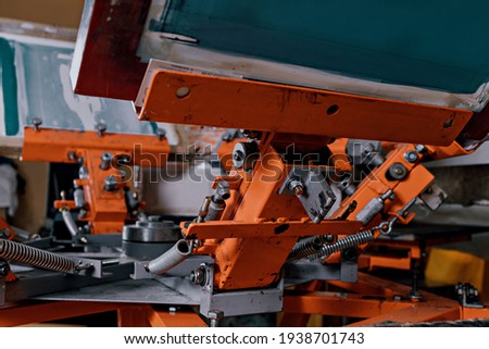 selective focus photo of print screening apparatus. serigraphy production. printing images on t-shirts by silkscreen method in a design studio
