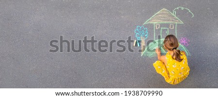 The child draws a house on the asphalt. Selective focus. kid. Royalty-Free Stock Photo #1938709990