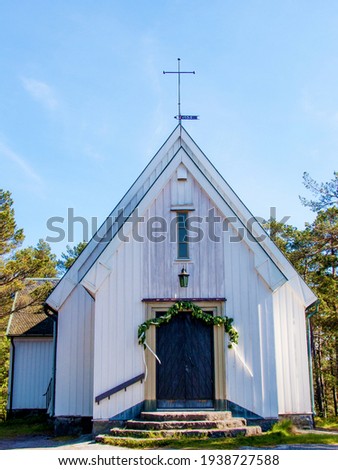 Old Swedish church on the Island of Sandhamn. Built in 1935, white wooden building. Flower decorations hanging above the entrance door. Summer day in the Stockholm archipelago. Scandinavian church.