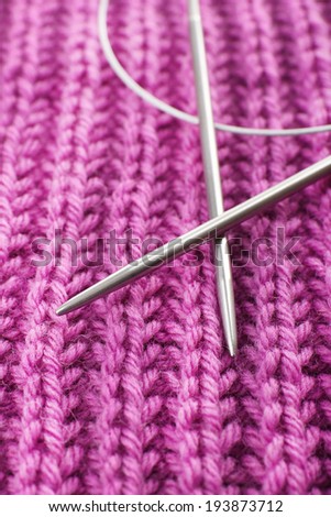 Two knitting spokes and knitted fabric close up
