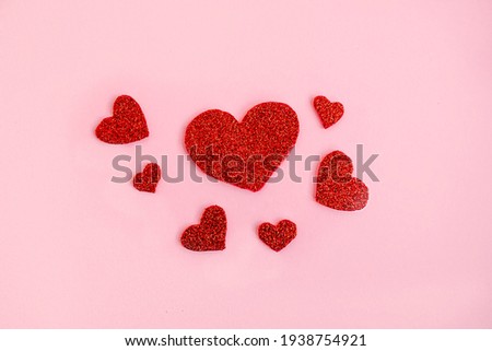 Love theme background with red glitter handmade hearts on pink background. Romantic concept