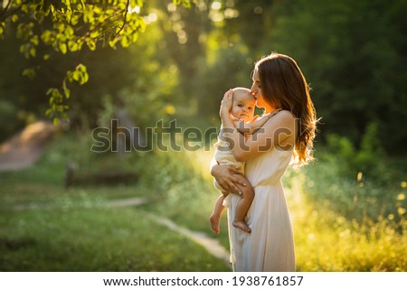 Young beautiful mother plays with her child outdoor. Royalty-Free Stock Photo #1938761857
