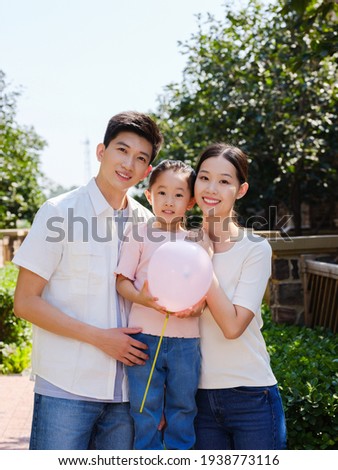 Happy family of three in the outdoor with a ballon