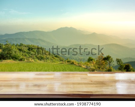 Wooden table on blur mountain morning or evening view landscape, Warm feeling in orange or brown tones. Royalty-Free Stock Photo #1938774190