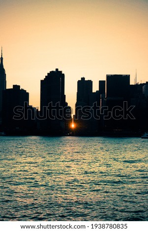 Manhattan New York City skyline seen at sunset with sunlight backlighting and seen between the buildings.