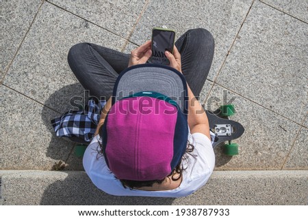 woman with cap and skateboard with phone cell