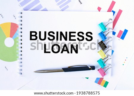 Notepad with text Business Loan, paper clips, blue pen on financial diagrams. Business concept