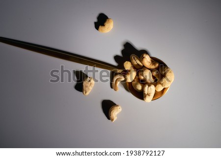 Golden spoon with cashew nuts and almonds on a gray background. Deep Shadows. High quality photo