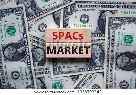 SPACs market symbol. Wooden blocks with words 'SPACs, special purpose acquisition companies market' on beautiful background from dollar bills, copy space. Business and SPACs market concept.