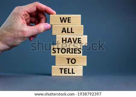 We all have stories to tell symbol. Wooden blocks with words 'We all have stories to tell'. Businessman hand. Beautiful grey background. Business, popular quotation concept. Copy space.
