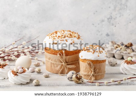 Traditional easter cake or sweet bread, pussy willow twigs, quail eggs and white meringues in shape of nest over white wooden table. Side view, close up. Easter treat, holiday symbol Royalty-Free Stock Photo #1938796129