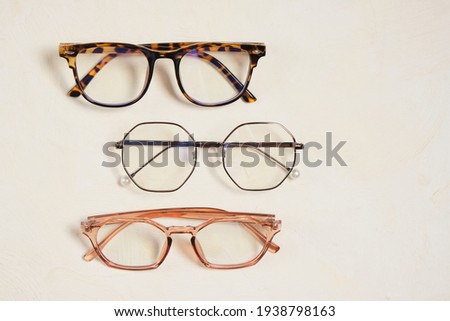 several fashionable stylish glasses on a beige background place copy top view, optics store concept Royalty-Free Stock Photo #1938798163
