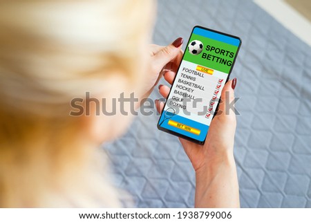 woman holding a mobile phone with sports betting website in the screen.