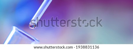 Close up of chemical test tube and pipette with drop of colorless liquid on purple background. Royalty-Free Stock Photo #1938831136