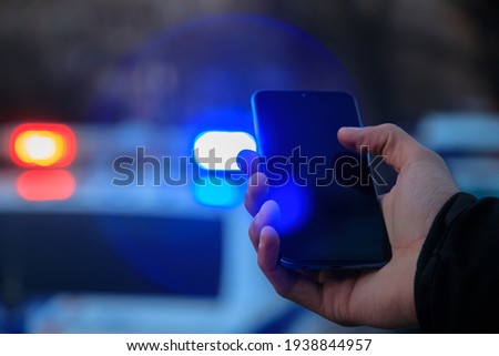 holding smartphone and police car background
