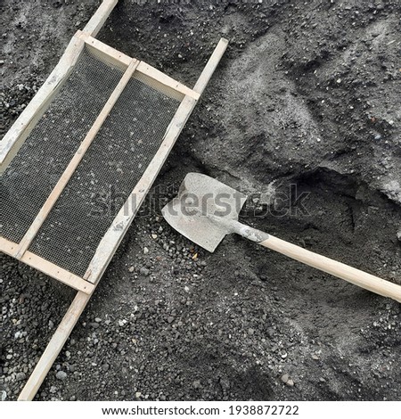 Metal sand shovel on the black sand