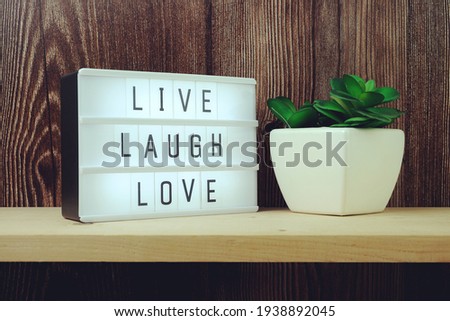 Live Laugh Love word in light box on wooden background