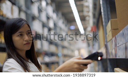 Female worker scanning products with barcode scanner in warehouse.