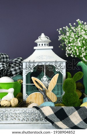 Easter on-tend farmhouse style vignette with wooden and moss bunnies with Easter eggs and buffalo plaid check decorations.
