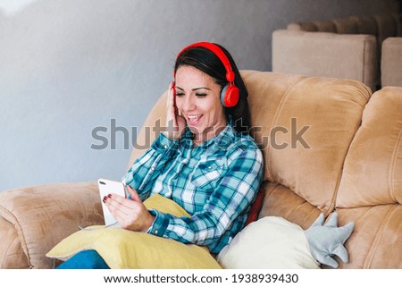 latin woman listening to music and keeping eyes closed while sitting on sofa at home in Mexico